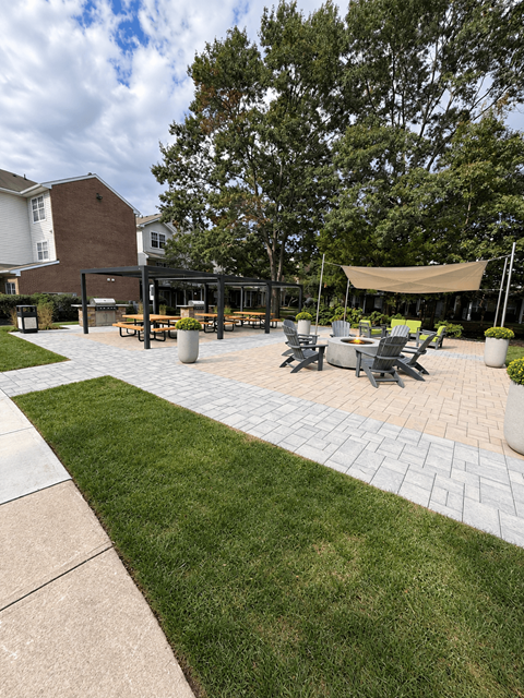 A patio with a table and chairs is surrounded by a grassy area.