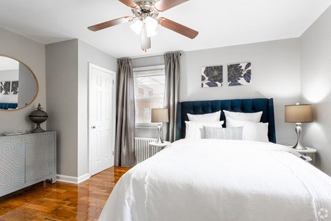 A bedroom with a large bed and a ceiling fan.