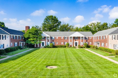 A large grassy field in front of a building with a brick chimney.