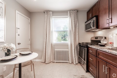A kitchen with brown cabinets and a white table.