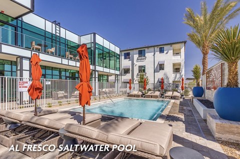 A saltwater pool is surrounded by a patio with chairs and umbrellas.