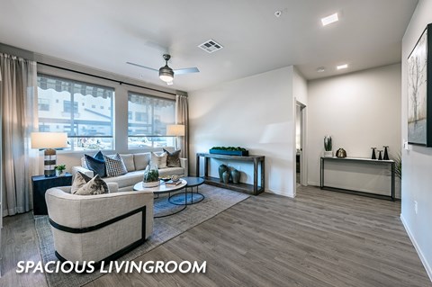 A spacious living room with a couch, a coffee table, and a window with curtains.