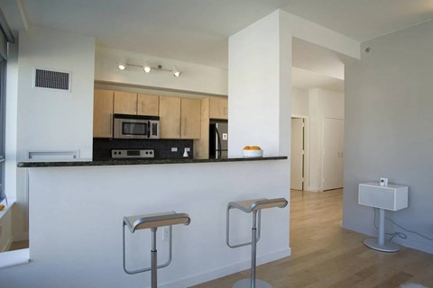 A kitchen with a white counter and two stools.