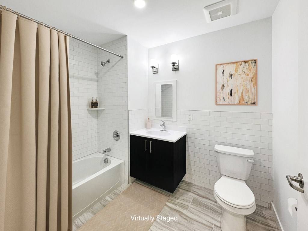 A bathroom with a white toilet, a white sink, a white bathtub, and a brown shower curtain.