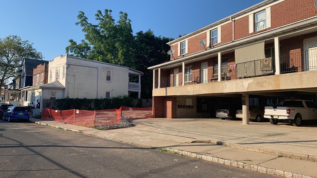A street view with a white building on the left and a red building on the right.