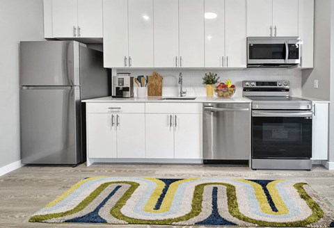 A modern kitchen with white cabinets and stainless steel appliances.