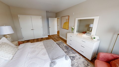 A bedroom with a large bed and a red chair.