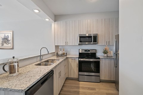 A modern kitchen with a granite countertop and stainless steel appliances.