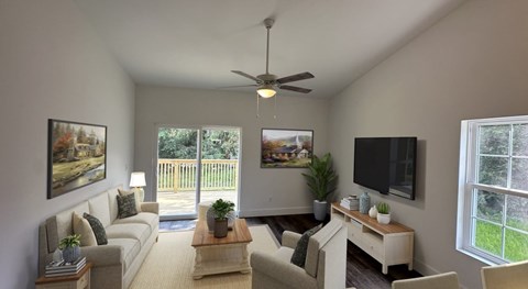 A living room with a couch, a coffee table, a television, and a ceiling fan.