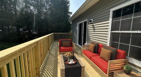 A wooden deck with a red couch and a table.