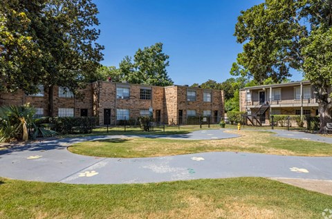 A playground area with a roundabout and a building in the background.