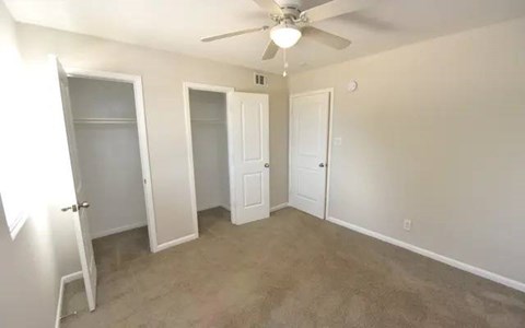 A room with a ceiling fan and three doors.