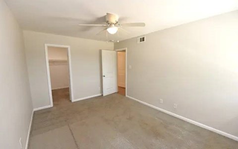 A room with a ceiling fan and a door.