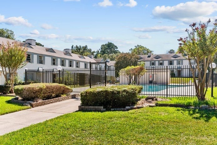 A row of houses with a fence and a pool in the foreground.