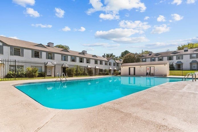 A swimming pool in front of a building with a fence around it.
