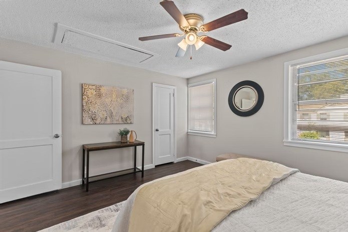 A bedroom with a bed, a table, a painting, a mirror, and a window.