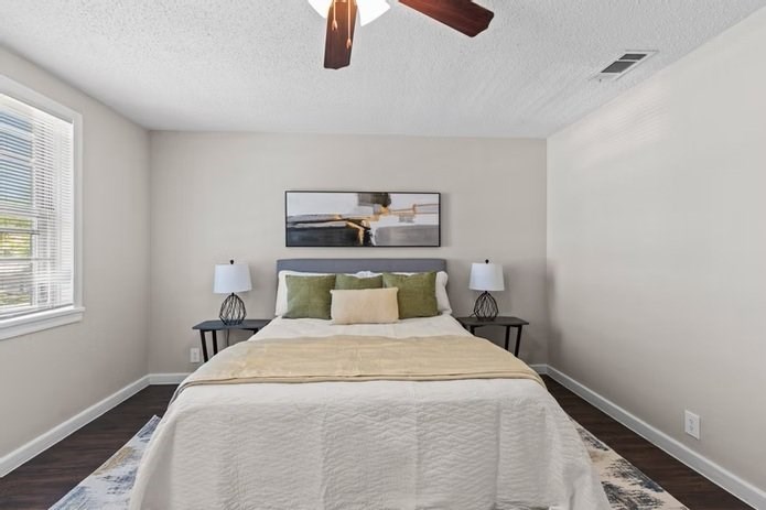 A bedroom with a bed, two lamps, and a painting on the wall.