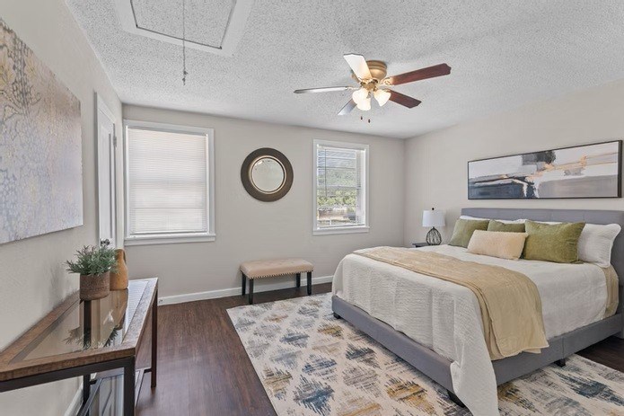A bedroom with a bed, a bench, a table, and a ceiling fan.