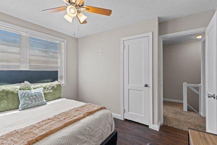A bedroom with a bed, a ceiling fan, and a window with blinds.