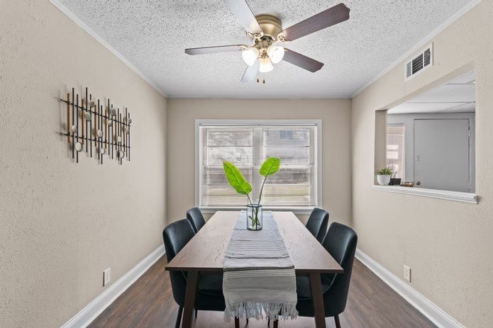 A dining room with a table, chairs, and a ceiling fan.