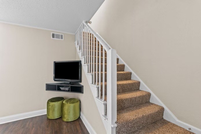 A staircase with a TV and stool.