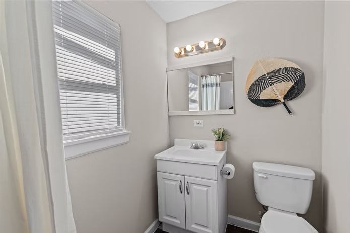 A white bathroom with a toilet, sink, and mirror.