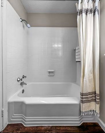 A white bathroom with a white tub and a white shower curtain.