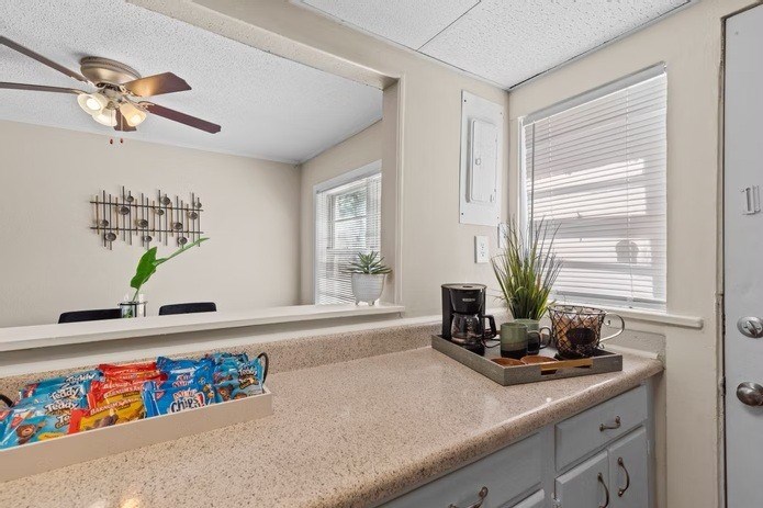 A kitchen with a counter, a fan, and a window.