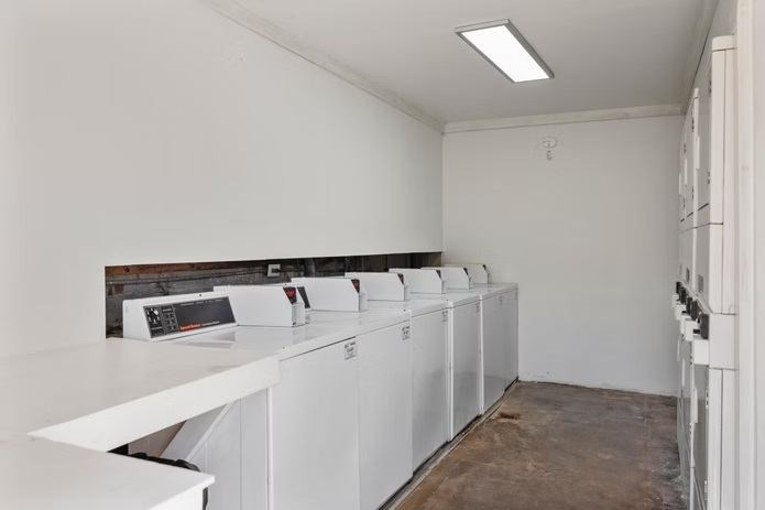 A row of washing machines are lined up in a laundry room.