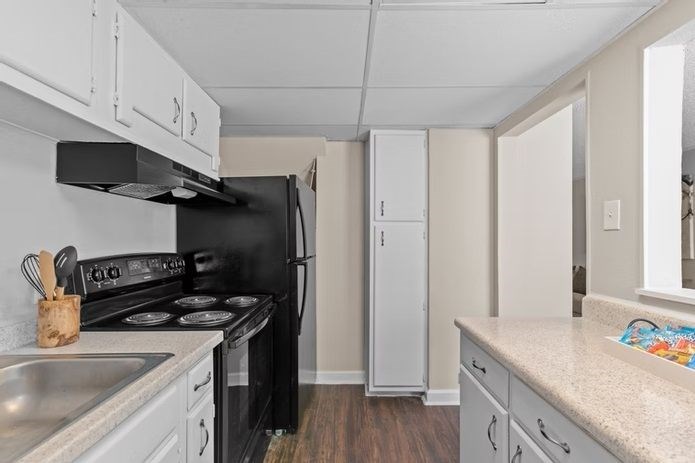 A kitchen with a black stove top oven and white cabinets.