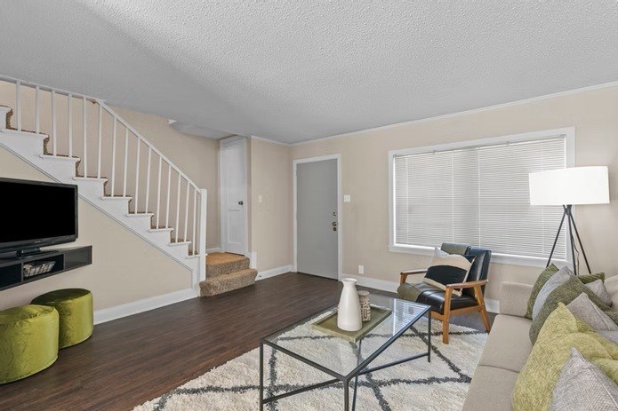 A living room with a staircase and a glass coffee table.