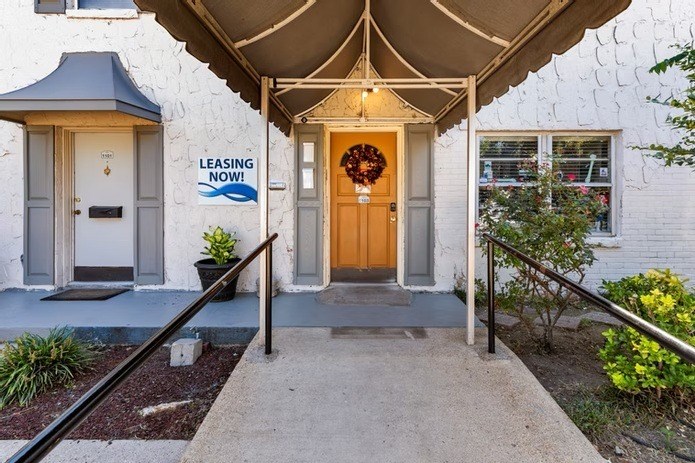 A white house with a leasing sign on the wall.