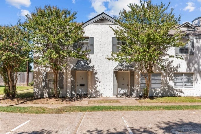 A white two-story building with a parking lot in front.