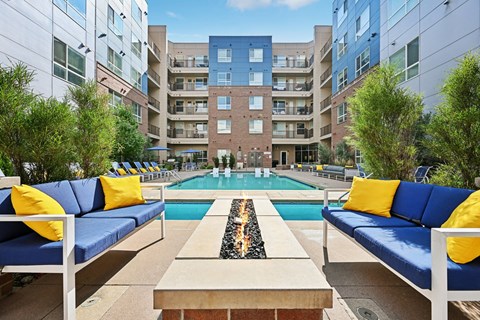 A pool surrounded by blue couches and yellow pillows.