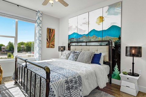 A bedroom with a large bed and a painting on the wall.
