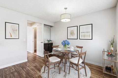 A dining room with a table set for two and a chandelier hanging from the ceiling.