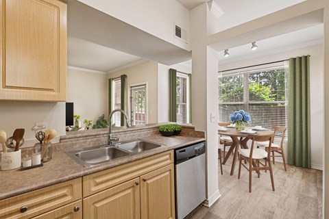 A kitchen with wooden cabinets and a dining table with chairs.