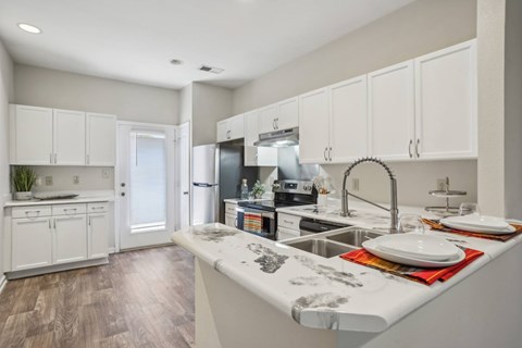 A kitchen with white cabinets and a wooden floor.