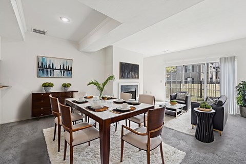 A dining room with a table set for six and a painting on the wall.
