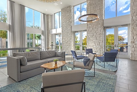 A living room with a grey couch, a coffee table, and a chandelier.