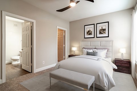 A bedroom with a large bed and a ceiling fan.
