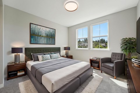 A bedroom with a large bed, a chair, and a painting on the wall.