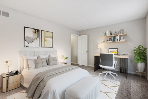 A bedroom with a large bed, a desk with a chair, and a potted plant.
