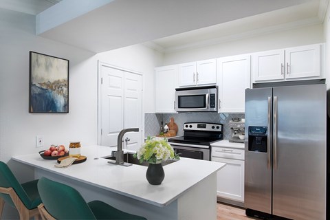 A kitchen with a white counter and green chairs.