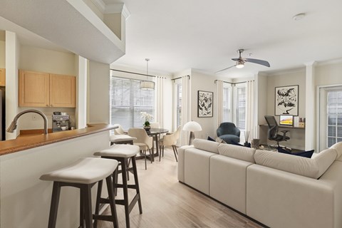 A modern kitchen with a bar area and a living room area with a couch and chairs.