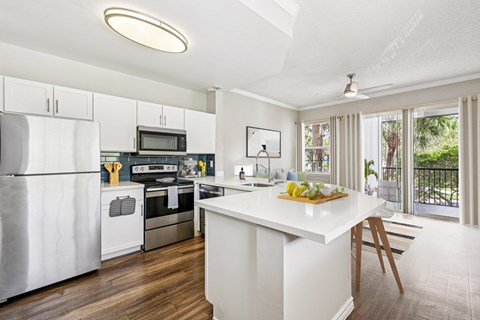 A kitchen with a white island and stainless steel appliances.