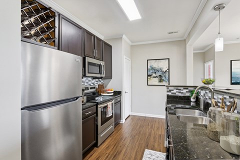 A modern kitchen with a stainless steel refrigerator and black cabinets.