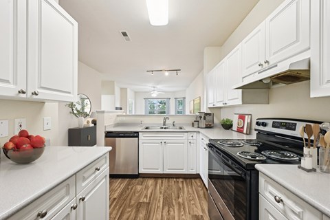 A modern kitchen with white cabinets and a black stove top oven.