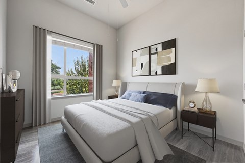 A bedroom with a large bed and a window with curtains.