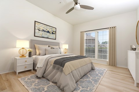 A bedroom with a large bed, a ceiling fan, and a painting on the wall.